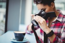 Mulher fotografando xícara de café enquanto estava em pé no restaurante — Fotografia de Stock