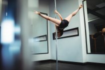 Bailarina de polo practicando pole dance en gimnasio - foto de stock