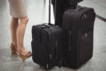 Sección baja de gente de negocios de pie con equipaje en la terminal del aeropuerto - foto de stock