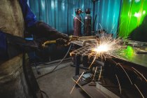Schweißerin arbeitet in der Werkstatt an einem Metallstück — Stockfoto