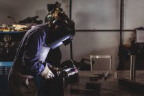 Seitenansicht einer Schweißerin, die in der Werkstatt an einem Metallstück arbeitet — Stockfoto
