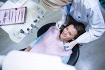 Стоматолог осматривает пациента с помощью инструментов в стоматологической клинике — стоковое фото