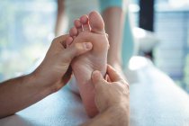 Geschnittenes Bild eines männlichen Physiotherapeuten, der einer Patientin in der Klinik eine Fußmassage gibt — Stockfoto