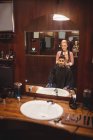 Femme coiffeur coiffant les cheveux du client dans le salon de coiffure — Photo de stock