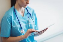 Медсестра с помощью цифрового планшета на стене больницы — стоковое фото