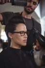 Женщина сушит волосы феном в парикмахерской — стоковое фото