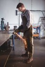 Schöner Schweißer schneidet Metall mit Elektrowerkzeug in Werkstatt — Stockfoto