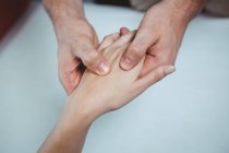 Image recadrée d'un physiothérapeute massant la main d'une patiente en clinique — Photo de stock