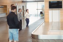 Menschen, die in der Gepäckausgabe am Flughafen auf ihr Gepäck warten — Stockfoto