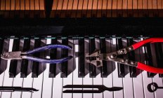 Крупним планом ремонтні інструменти, що зберігаються на старій клавіатурі піаніно — стокове фото