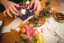 Крупним планом жіночий флорист готує квітковий букет в її квітковому магазині — стокове фото
