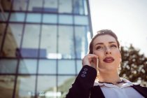 Бізнес-леді розмовляють по телефону поза офісною будівлею — стокове фото
