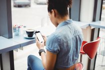 Жінка використовує мобільний телефон, сидячи в ресторані — стокове фото