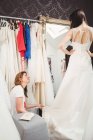 Женщина примеряет свадебное платье в студии при содействии креативного дизайнера — стоковое фото
