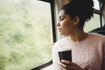Жінка тримає одноразову чашку кави, сидячи в поїзді — стокове фото