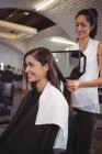 Улыбающаяся парикмахерша показывает женщине свою стрижку в зеркале в салоне — стоковое фото
