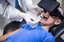 Ragazzo che utilizza cuffie realtà virtuale durante una visita dentale in clinica — Foto stock