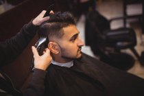 Мужчина стрижёт волосы триммером в парикмахерской — стоковое фото