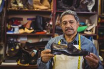 Sapateiro examinando um sapato na oficina — Fotografia de Stock
