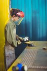 Женщина-сварщик с помощью циркулярной пилы в мастерской — стоковое фото