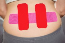 Imagen recortada de paciente femenina con cinta adhesiva en la espalda en la clínica - foto de stock