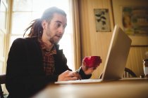 Homem hipster inteligente usando laptop em casa — Fotografia de Stock