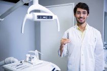 Портрет усміхненого стоматолога стоїть з стоматологічними інструментами в стоматологічній клініці — стокове фото