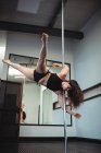 Hermosa bailarina polaca practicando pole dance en gimnasio - foto de stock