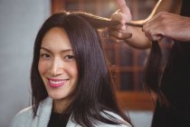 Hairdresser working on smiling client at hair salon — Stock Photo