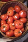 Primer plano de tomates frescos en canasta de mimbre en el supermercado - foto de stock