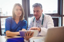 Доктор обговорює з медсестрою цифровий планшет у лікарні — стокове фото