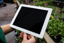 Обрезанное изображение женщины-флориста с помощью цифрового планшета в центре сада — стоковое фото