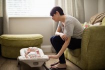 Madre seduta sul divano e guardando il suo bambino in soggiorno a casa — Foto stock