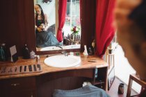 Uomo che riceve massaggio facciale da barbiere donna in negozio di barbiere — Foto stock
