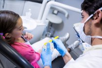 Dentista explicando modelo de boca a paciente joven en clínica dental - foto de stock
