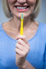 Середина усміхненої жінки, що тримає зубну щітку — стокове фото
