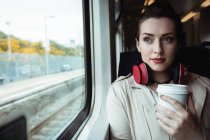 Молода жінка тримає одноразову чашку біля вікна в поїзді — стокове фото