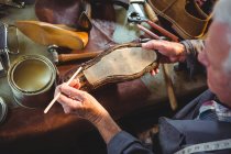 Overhead view of shoemaker applying glue on shoe sole in workshop — Stock Photo