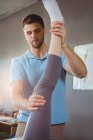 Fisioterapeuta masculino dando massagem nas pernas para paciente do sexo feminino na clínica — Fotografia de Stock