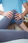 Imagem recortada de fisioterapeuta masculino dando massagem no joelho para paciente do sexo feminino na clínica — Fotografia de Stock