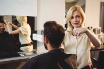 Coiffeur coupe les cheveux du client au salon de coiffure — Photo de stock