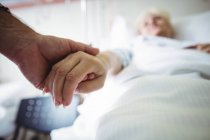 Senior hält Seniorin im Krankenhaus die Hand — Stockfoto