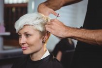 Sorridente femmina ottenere i capelli tagliati al salone — Foto stock