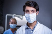 Porträt des Zahnarztes und der Zahnarzthelferin mit chirurgischen Masken in der Zahnklinik — Stockfoto