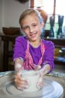 Portrait of happy girl making pot in pottery workshop — Stock Photo