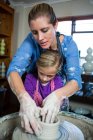 Close-up of female potter assisting girl in pottery workshop — Stock Photo