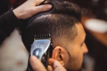 Homme se faire couper les cheveux avec tondeuse dans le salon de coiffure — Photo de stock