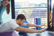 Physiotherapeutin hilft männlicher Patientin auf Trainingsball in Klinik — Stockfoto