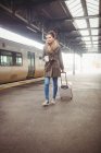 Mujer llevando equipaje mientras camina en la plataforma de la estación de tren - foto de stock