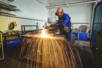 Male welder working on piece of metal in workshop — Stock Photo